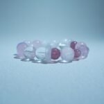 A Lumoola beaded bracelet featuring clear quartz and varying shades of pink crystals. The pink stones symbolize the gentle, compassionate heart chakra energy and healing warmth inspired by the Ark Care autism organization.