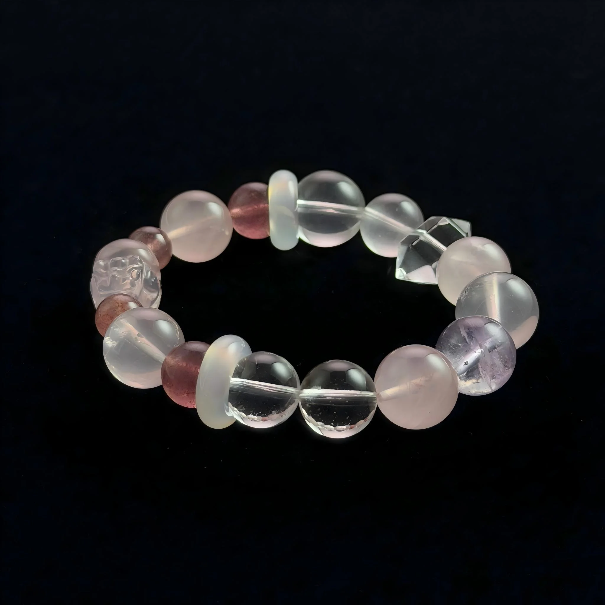 A top-down view of a multi-gemstone crystal bracelet on a black background. It features bead of reddish strawberry quartz, pale pink quartz, translucent white agate, a single purple amethyst bead, clear quartz spheres, and a central carved clear quartz Pixiu figure.