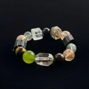 Five Elements crystal bracelet featuring raw black tourmaline logs, multi-color tiger eye beads, and green rutilated quartz for feng shui wealth and protection.